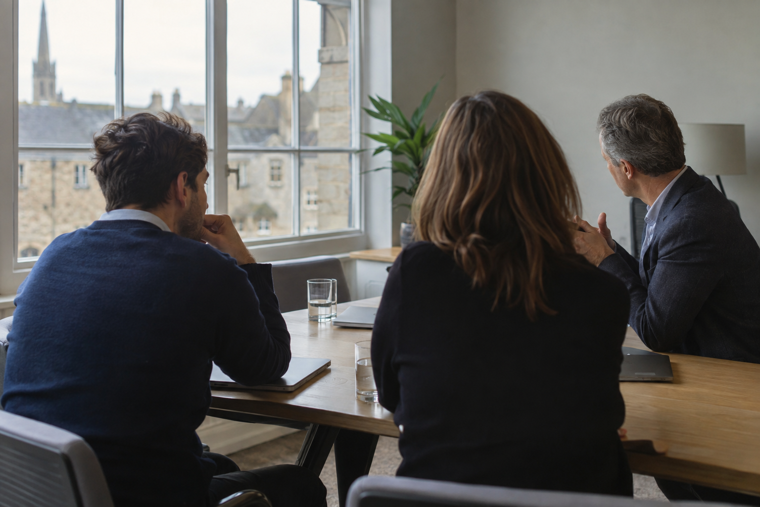 Anonymous business advisers and founders discuss international expansion around an office table in Oxfordshire, UK.